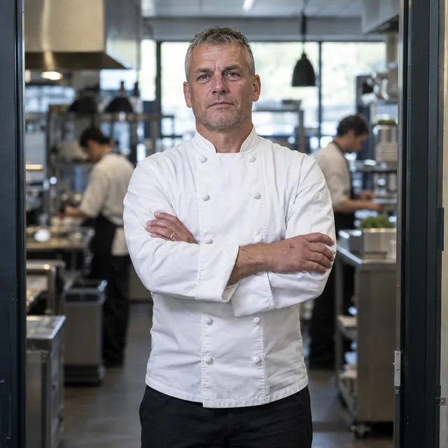 Chef-kok met de armen over elkaar in de deur van zijn keuken