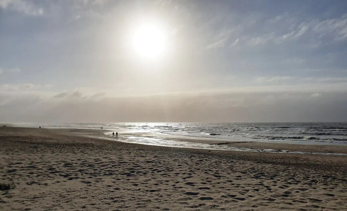 Het rustige strand van Kijkduin met de zon door de nevel