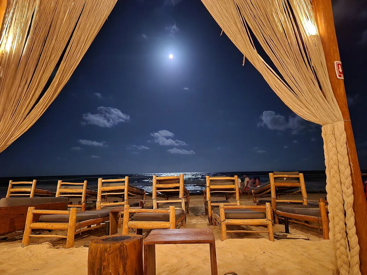 Strandclub bij avondlicht met loungestoelen aan zee